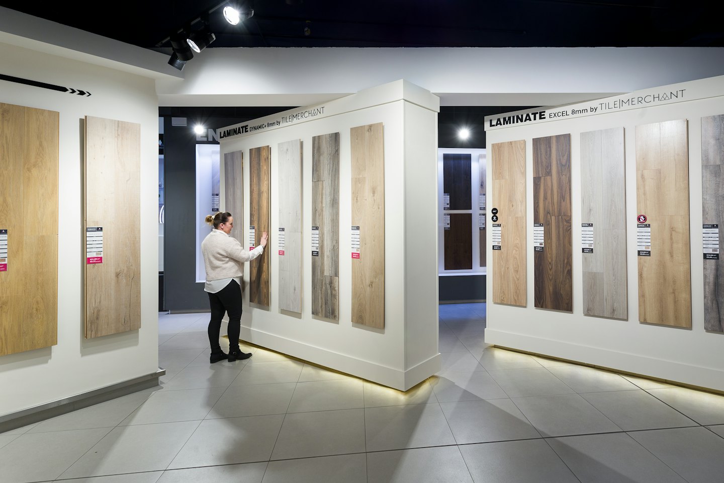 Woman choosing wood-look laminate flooring samples in a showroom.