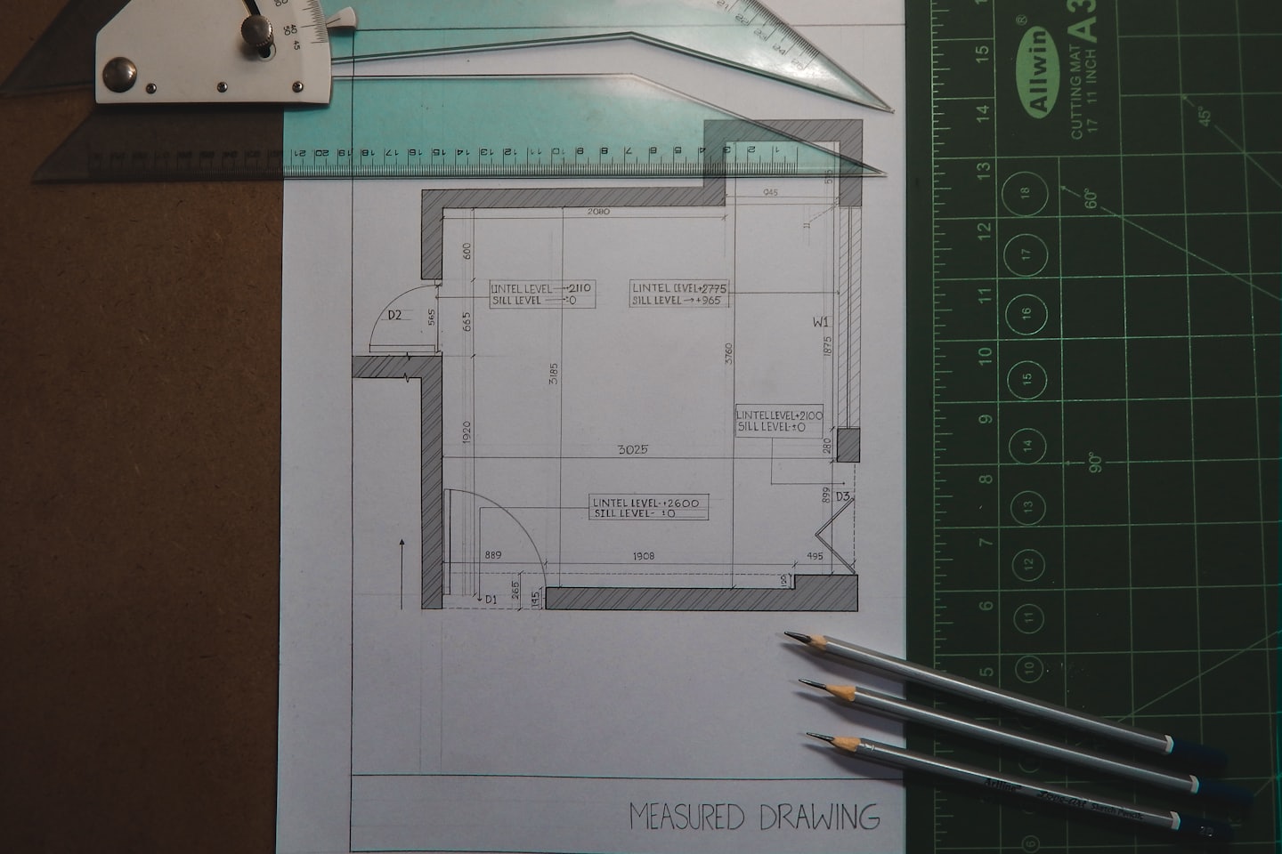 Architectural floor plan and drafting tools on a desk.